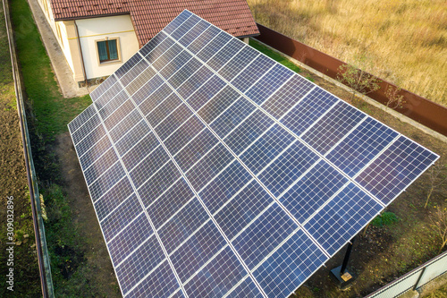 Aerial view of big blue solar panel installed on ground structure near private house.
