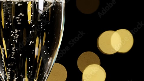 champagne in a glass, concept of new year and Christmas champagne pouring in a glass dark background with beautiful yellowbokeh. champagne pour into a glass. Close up shot. Slow motion photo
