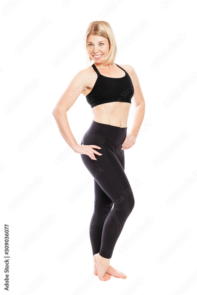 A young smiling woman in black sportswear is standing full length. Isolated over white background. Vertical. A young smiling woman in black sportswear is standing full length. Isolated over white background. Vertical.