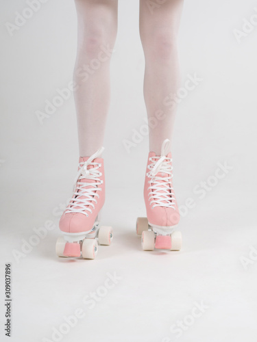 Cropped body closeup female athletic slim legs in white tights with a pink quad vintage rollers on a white background