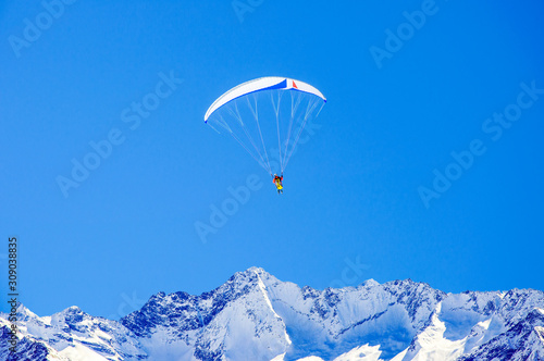 Skiing and paragliding in Austrian Alps. Unrecognizable skier and paraglider flying over Zillertal Alps near Tux glacier and Hintertux ski resort in Tuxertal valley