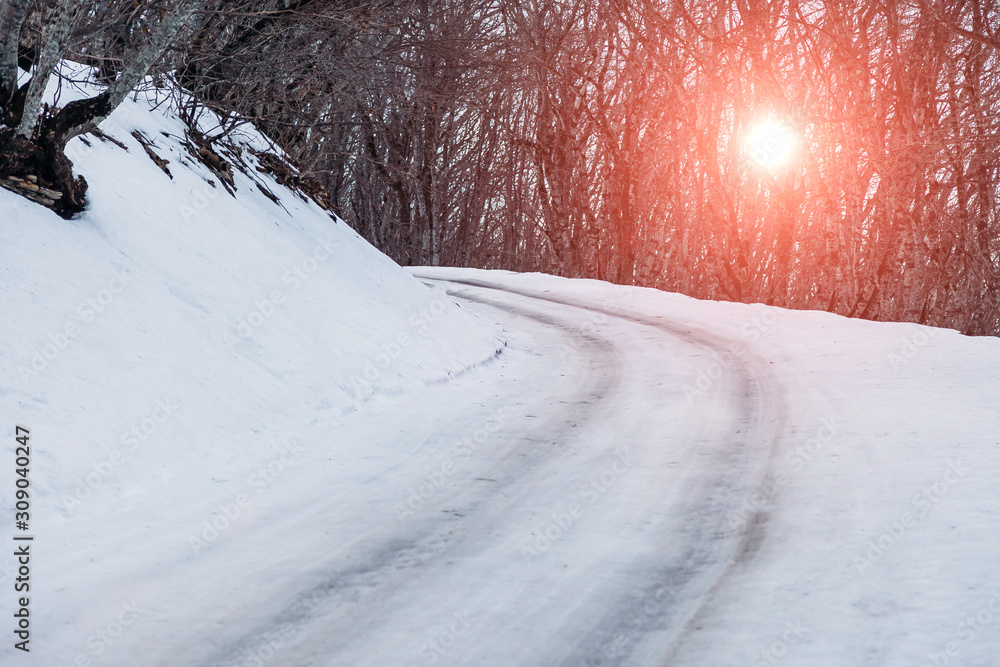 first snow on the road in forest at sunset first snow on the road in forest at sunset