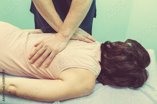 Male caucasian young professional doctor makes massage to a patient with problem from back