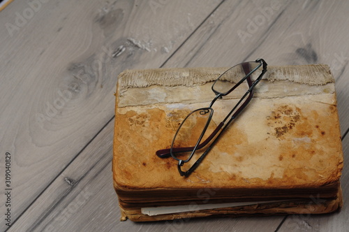 Optical glasses and old book on grey woodboard (ID: 309040829)