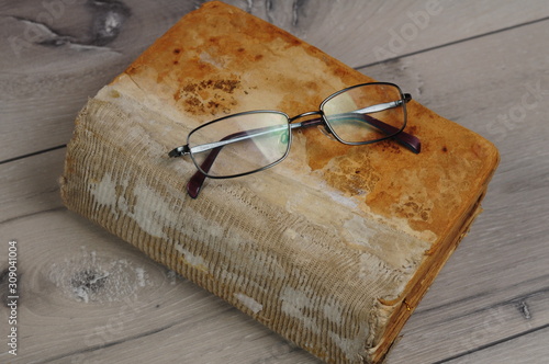 Optical glasses and old book on grey woodboard (ID: 309041004)