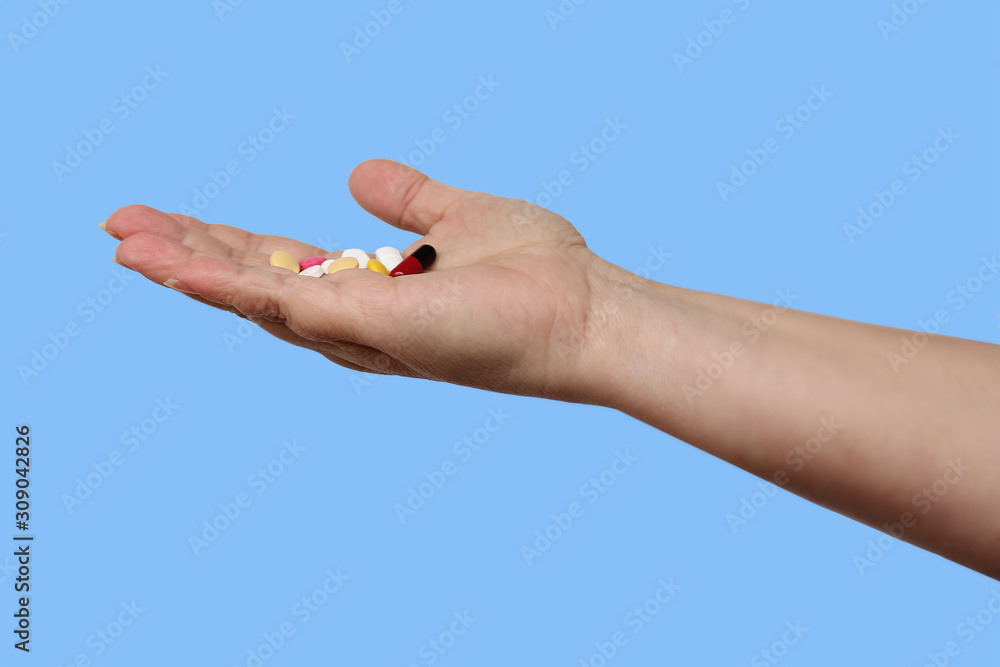 female hand holds out, offering, a handful of colored pills and capsules, close-up, color background, copy space, concept of medical care, treatment female hand holds out, offering, a handful of colored pills and capsules, close-up, color background, copy space, concept of medical care, treatment
