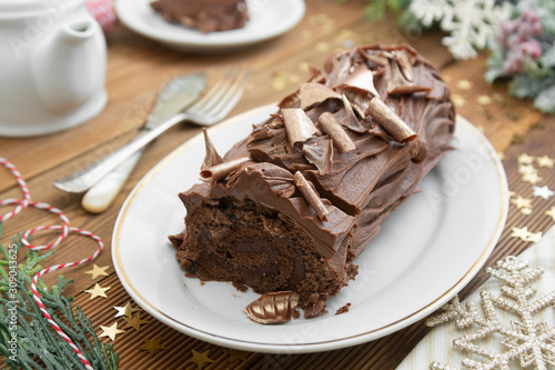 Christmas chocolate swiss roll isolated on a wooden background. Chocolate sweet dessert. Pastry for breakfast or tea.