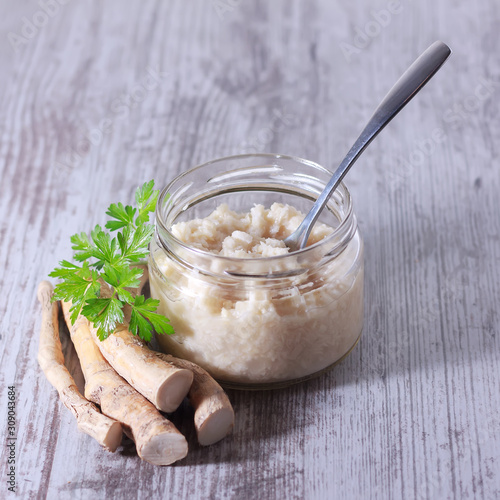 Spicy horseradish sauce in glass jar isolated on white photo