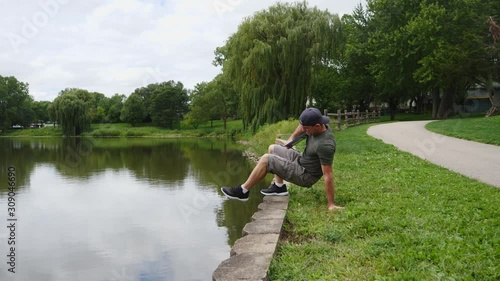 Man sitting by a lake, river, pond, working on a laptop computer, typing.