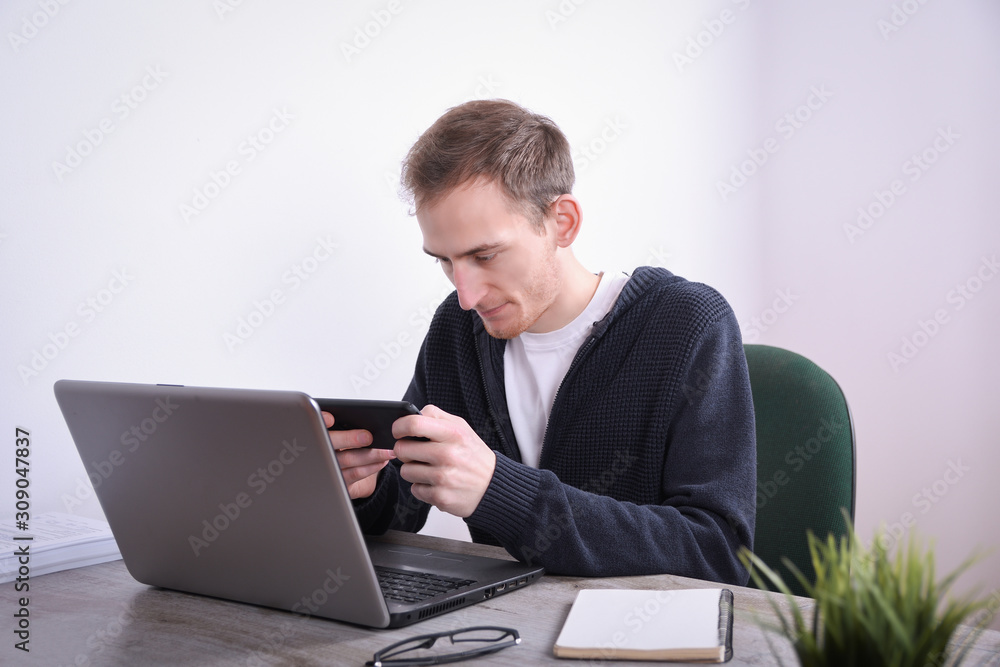 Portrait of young business man sitting at his desk desktop laptop technology in the office.Internet marketing, finance, business concept Portrait of young business man sitting at his desk desktop laptop technology in the office.Internet marketing, finance, business concept