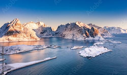 Amazing aerial view of Lofoten Islands nature from drone, winter sunrise snowy scenery of village Reine, Sakrisoy and Hamnoy during beautiful mountain ridge with alpenglow, scene over polar circle.