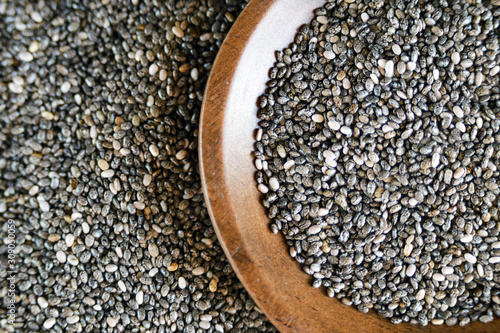 Edible seeds of chia, Salvia hispanica, a flowering plant of the mint family. .Close-up. Chia seeds in a plate of natural olive wood. Product for beauty and health. Proper nutrition. Blurry.