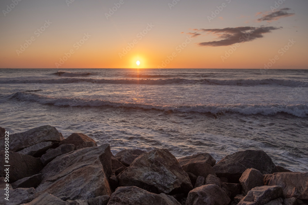 Bonito pôr do sol no mar com ondas e pedras