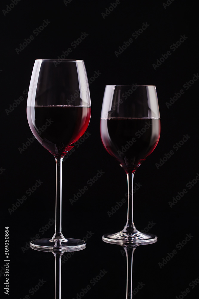  Two glasses with red wine on a black background. Wine on the dark