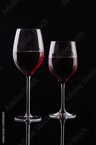  Two glasses with red wine on a black background. Wine on the dark