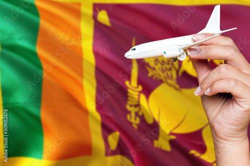 Sri Lanka travel concept. Woman holding a miniature plane on national flag background. Holiday and voyage theme with copy space for text.