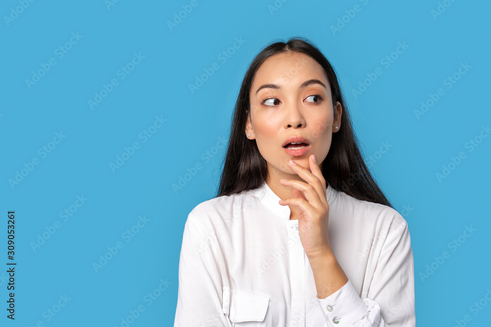Freestyle. Young woman wearing shirt standing isolated on blue looking aside mouth opened surprised close-up Freestyle. Young woman wearing shirt standing isolated on blue looking aside mouth opened surprised close-up