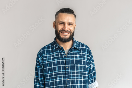 Mature bearded man smiling wide, standing on grey background