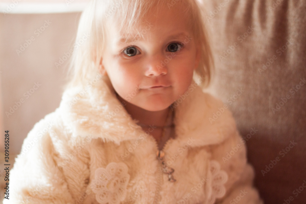 little girl in a white fluffy jacket decorated with lace flowers