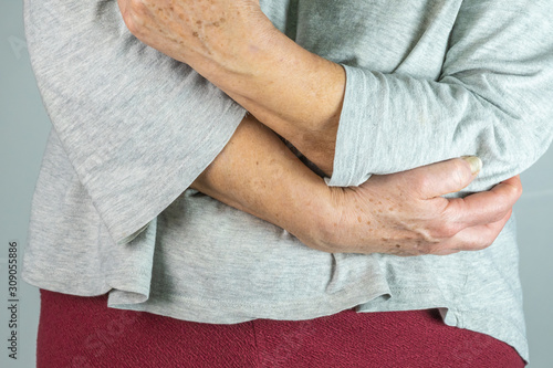 caucasian elderly woman with her hand on her elbow, isolated on White background