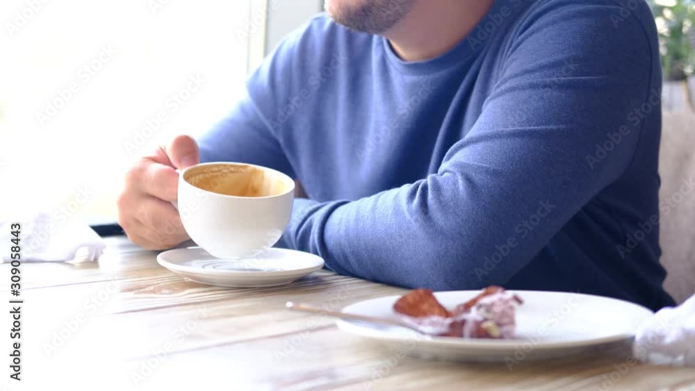 Morning coffee. Cropped caucasian man in blue drinking coffee ot tea in restaurant, cafe. Closeup man hands with white cup Morning coffee. Cropped caucasian man in blue drinking coffee ot tea in restaurant, cafe. Closeup man hands with white cup