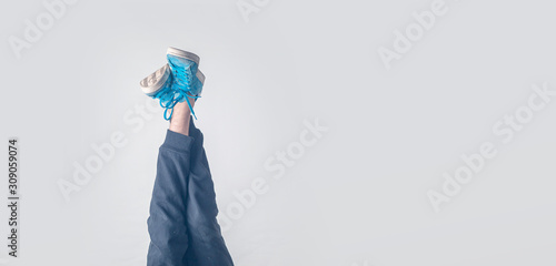 Slika na platnu fashion trendy concept, simple legs in sneakers in air against the wall, upside