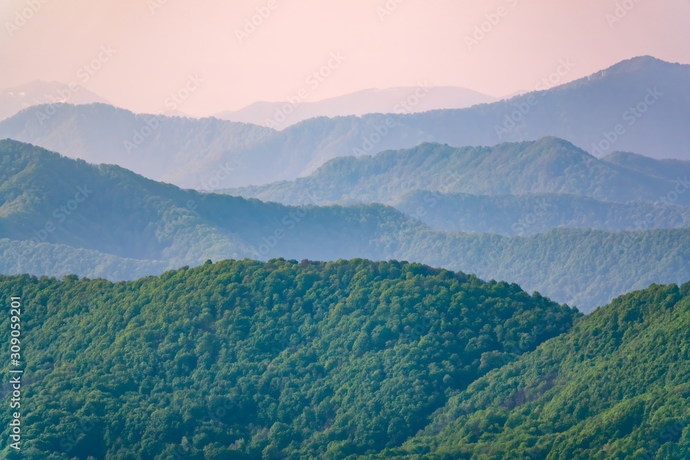 Obraz premium Layers of mountains in the haze during sunset. Beautiful sunset in the hills and mountains. Beautiful sunset in a hilly valley with fog in the lowlands.