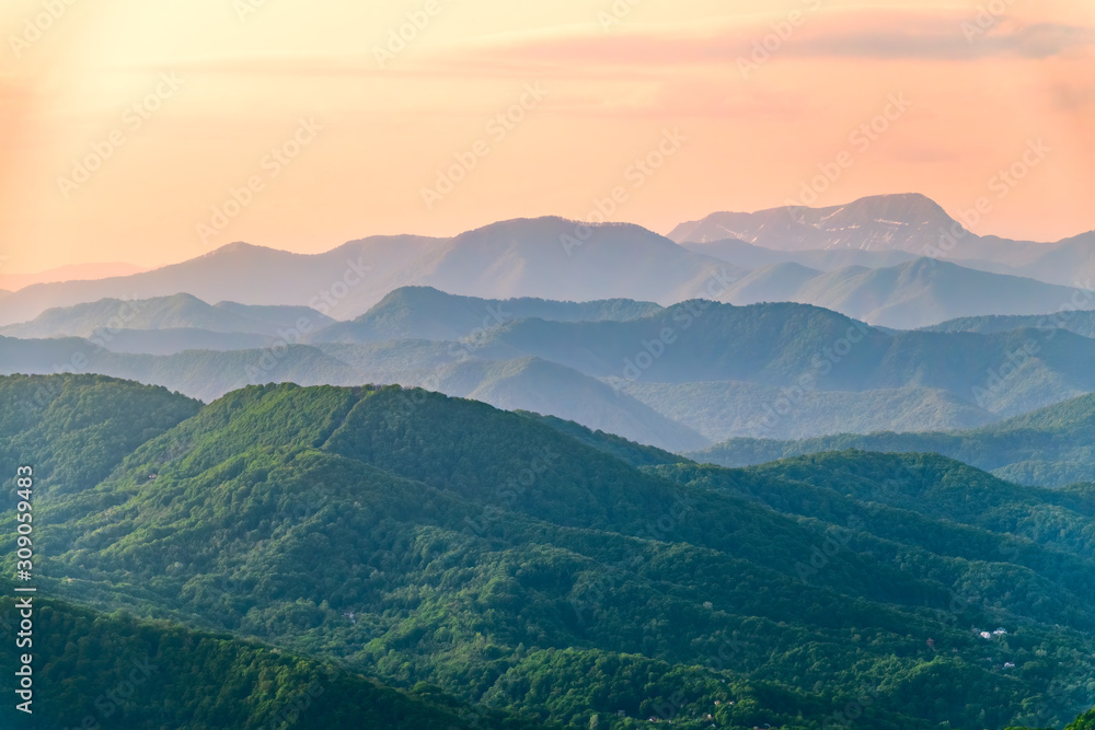 Layers of mountains in the haze during sunset. Beautiful sunset in the hills and mountains. Beautiful sunset in a hilly valley with fog in the lowlands.