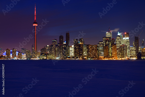 Blue hour from snow covered frozen Lake Ontario of Toronto city skyline lights at night in winter