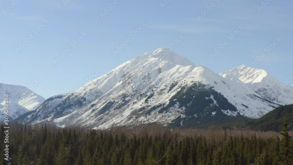 Aerial, rising, drone shot, over Alaskan wilderness, towards huge snowy peaks, in the Chugach Mountains of Alaska, on a sunny day, in Kenai Peninsula, USA Aerial, rising, drone shot, over Alaskan wilderness, towards huge snowy peaks, in the Chugach Mountains of Alaska, on a sunny day, in Kenai Peninsula, USA