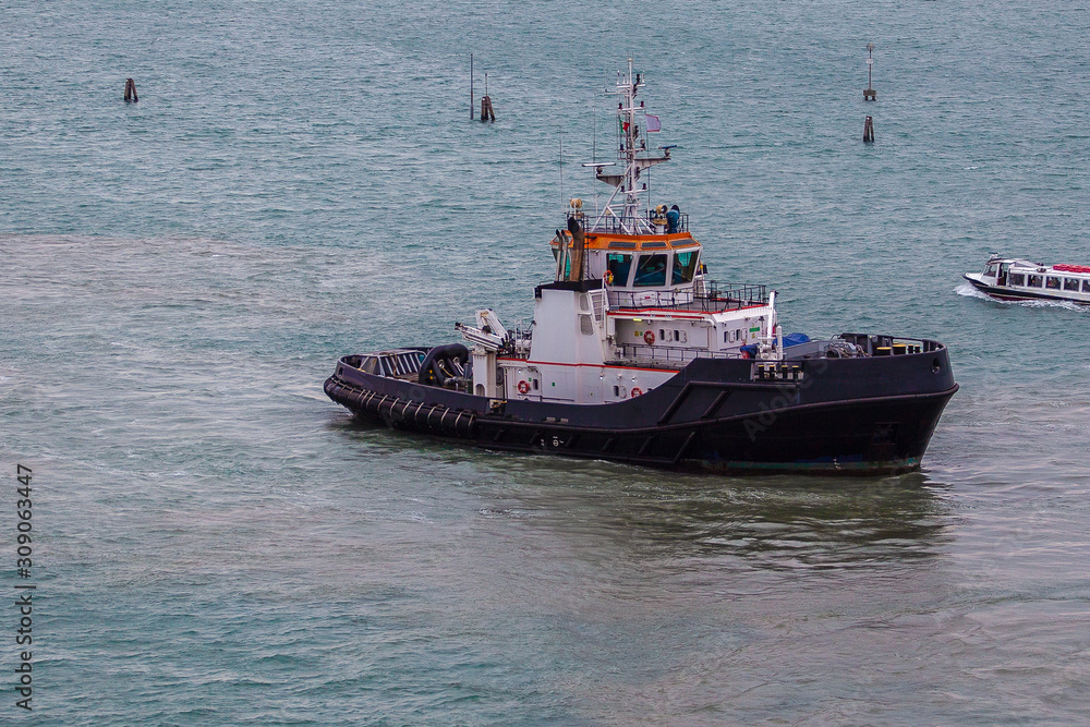 Tugboat working in the port of Venice, Italy. Concept: maritime transport, commerce, shipbuilding industry, maritime trade Tugboat working in the port of Venice, Italy. Concept: maritime transport, commerce, shipbuilding industry, maritime trade
