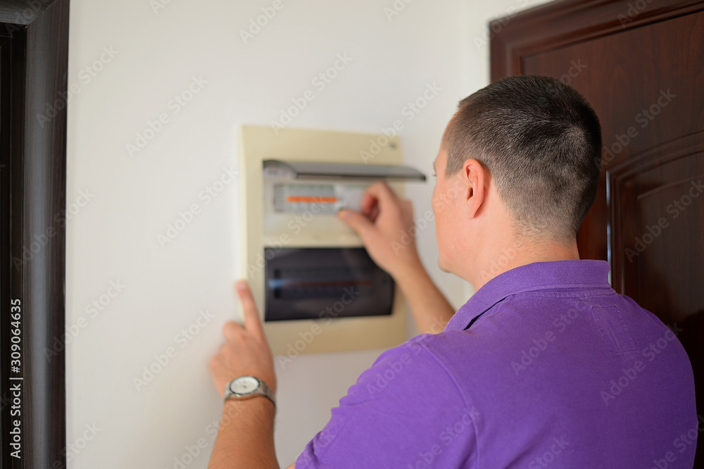 Man checking a voltage and fixing a switchboard in his home