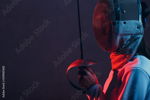 Fencer woman in mask profile portrait with fencing sword.