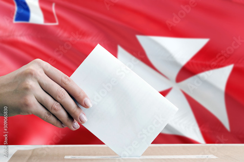 Wallis And Futuna election concept. Side view woman putting a ballot in a box on national flag background.