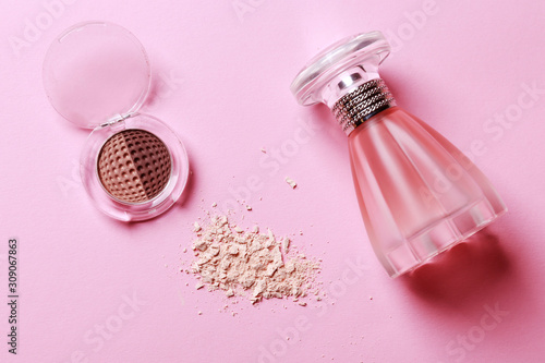 Bottle of pink perfume on pink pastel background. Beauty woman gentle concept. Makeup cosmetics. Eyeshadow crushed palette, colourful eye shadow powder on pink background with copy space. photo