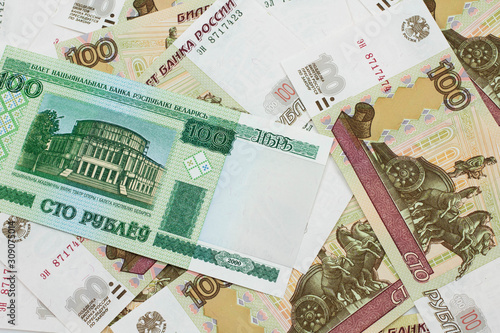 A green hundred ruble bank note from Belarus on a bed of Russian one hundred ruble bank notes close up in macro