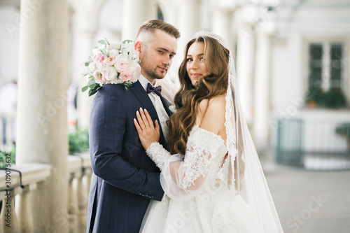 Beautiful young wedding couple posing with bouquet of flowers in hands