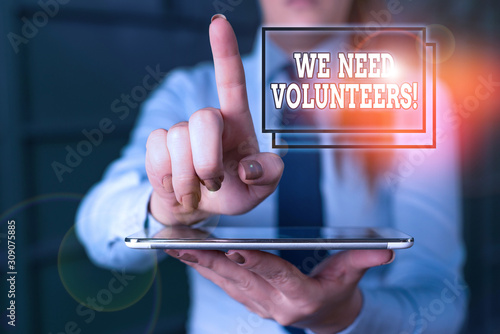 Word writing text We Need Volunteers. Business photo showcasing someone who does work without being paid for it Blurred woman in the background pointing with finger in empty space