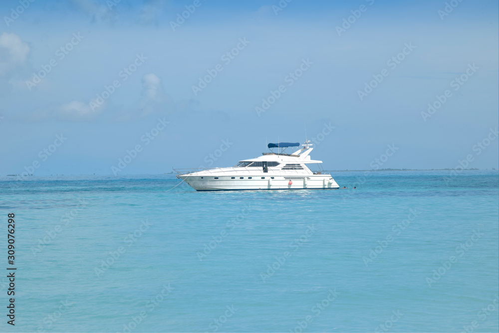 Super luxury motor yacht stopped in front of a white Caribbean beach. White beach and crystal clear turquoise sea. Isla Mujeres Mexico.