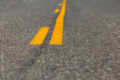 Photography low angle closeup view of yellow dividing and no passing lines and stripes in mi