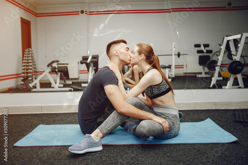 Cute couple in a gym. Man and woman in a sportswear. Guy and his girlfriend training