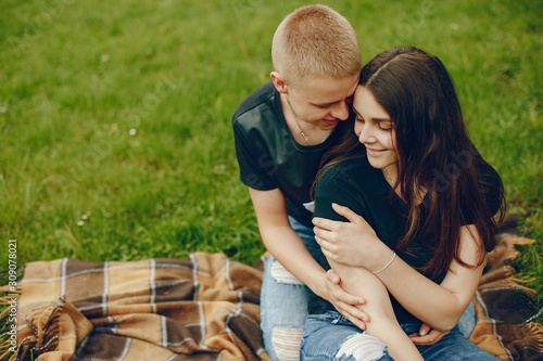 Lovely couple in a summer park. Boy with his girlfriend. Girl with guy sitting on a grass