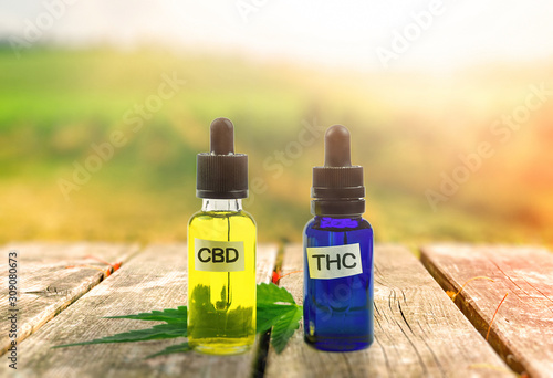 THC and CBD oil bottles on wooden table photo