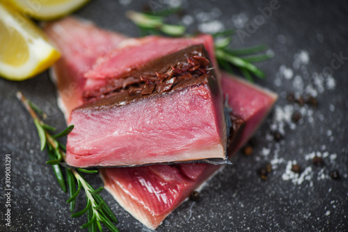 Fresh fish fillet sliced for steak or salad with herbs spices rosemary and lemon Raw fish seafood on black plate background , Longtail tuna , Eastern little tuna fillet ingredients for cooking food