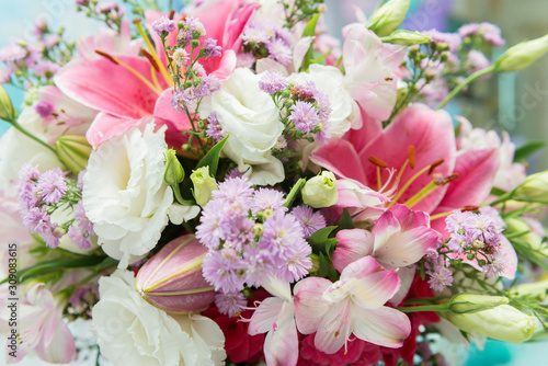 Close up of pink lily flowers around by roses  carnation flowers and green leaves. Close up of beautiful colorful bouquet of flowers with lily and roses. Different kind of flowers. Selective focus.