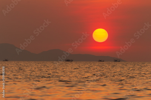 View of the evening sunset. Kathing Lai Beach Banglamung Chonburi province. The light produced is bright red due to dust pollution in the air causing the image to be colored.