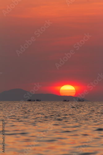 View of the evening sunset. Kathing Lai Beach Banglamung Chonburi province. The light produced is bright red due to dust pollution in the air causing the image to be colored.