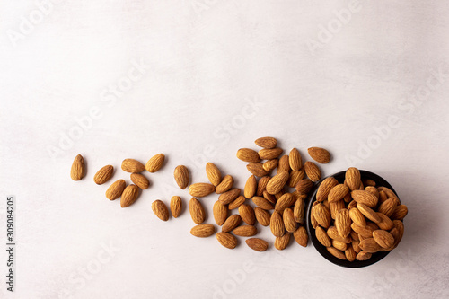 natural and organic almonds in a black bowl, top view.