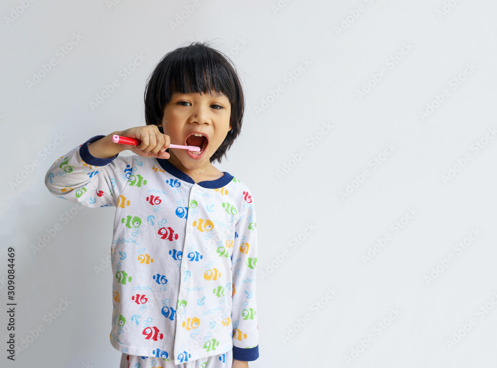 Little boy brushing his teeth In pajamas copyspace on gray background Little boy brushing his teeth In pajamas copyspace on gray background