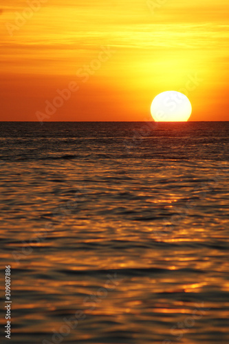 Fototapeta Naklejka Na Ścianę i Meble -  The setting sun setting in the sea, in the foreground the sea.